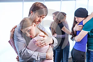 Man hugs a woman on foreground.