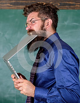 Man hungry for knowledge. He needs new information. Thirst of knowledge. Teacher bearded man bites modern laptop