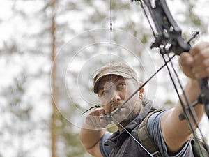 Man hunts in the forest with a bow. The hunter aims.