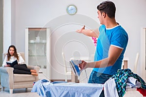 The man husband ironing at home helping his wife