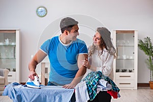 The man husband ironing at home helping his wife