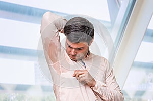 Man with hyperhidrosis sweating under armpit in office photo