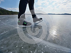 Man ice skating on frozen lake. Thin ice with deeep cracks below man