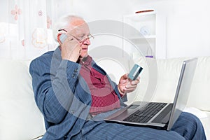 Man indoors using telephone and looking at credit card smiling