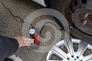 Man inflates tire with air and checking air pressure with gauge pressure in service station. Flat tire concept