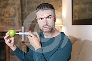 Man injecting liquid inside apple