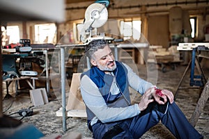 Man with an injured hand after accident at work in the carpentry workshop.