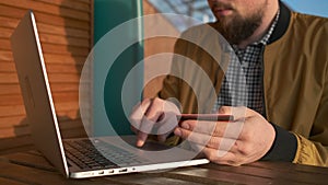 Man is inputting number of credit card in payment form on site using laptop