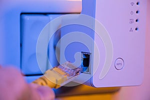 Man insert ethernet cable into WiFi extender device which is in