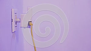 Man insert WiFi repeater into electrical socket on the wall and plug in a ethernet cable into it