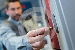 man inserting coin in to vending machine
