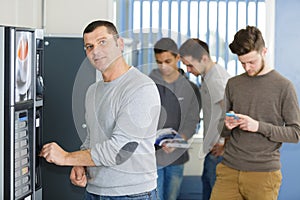 Man inserting coin in vending machine