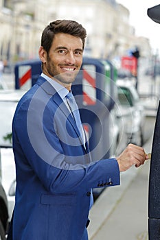 man inserting coin in vending ticket machine