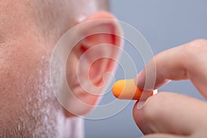 Man Inserting Earplug In His Ear