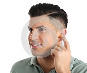 Man inserting foam ear plug on white background
