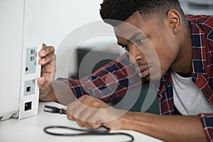 man inserting power lead into computer