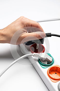 Man inserting power plug into extension cord on white background. Electrician`s professional equipment