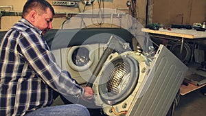 The man inserts the bolts into the holes in the drum of the washing machine.