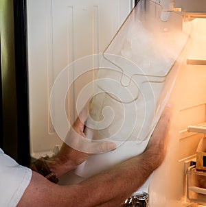 Man inserts icemaker reservoir into a refrigerator photo