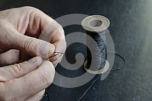 The man inserts the thread into the eye of the needle