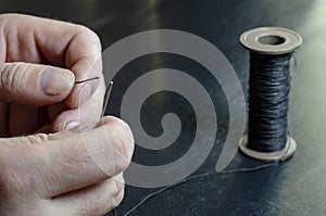 The man inserts the thread into the eye of the needle