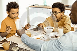 Man insisting that one of his sons need to drink the milk.