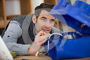 man inspecting blue plastic box housing electrical component