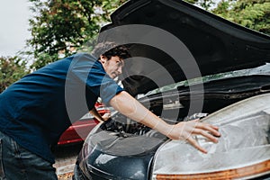 Man inspecting car engine with hood open on a sunny day photo