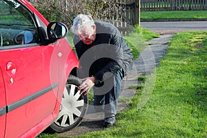 Man inspecting car tires or tyres.