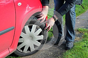 Man inspecting car tires or tyres.