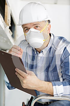 Man inspecting derelict property wearing dust mask