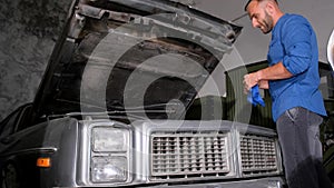 Man inspecting vehicle under hood in garage, Automotive design details visible