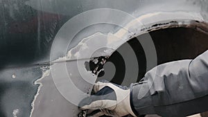 A man inspects car body in order to clean rust on it with an air blast and scraper