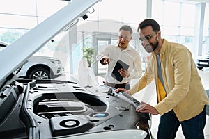 Man inspects a car under the hood