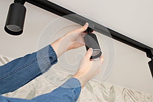 A man install a spot track LED light in the ceiling.