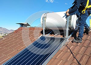 Man installing alternative energy photovoltaic solar panels on roof