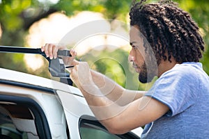 man installing car roof rack on car