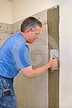 Man installing ceramic tile in bathroom