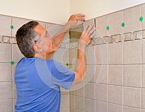 Man installing ceramic tile in bathroom