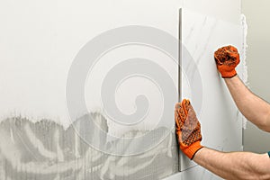Man installing ceramic tile on wall, space for text.