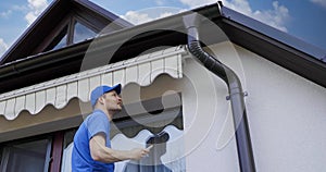 Man installing and checking awning on house facade wall over the balcony window