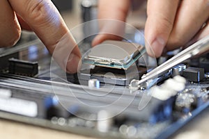 Man installing computer chip onto motherboard at table, closeup