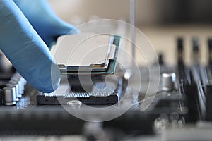 Man installing computer chip onto motherboard at table, closeup