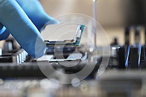 Man installing computer chip onto motherboard at table, closeup