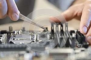 Man installing computer chip onto motherboard at table, closeup