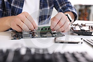 Man installing computer chip onto motherboard at white table, closeup
