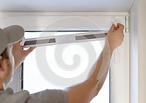 Man installing gray pleated blinds on the window