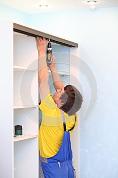 Man installing guide rails for sliding wardrobe in photo