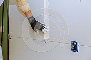 Man installing gypsum plasterboard construction of housing project with drywall installed