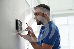 Man installing home security system on wall in room